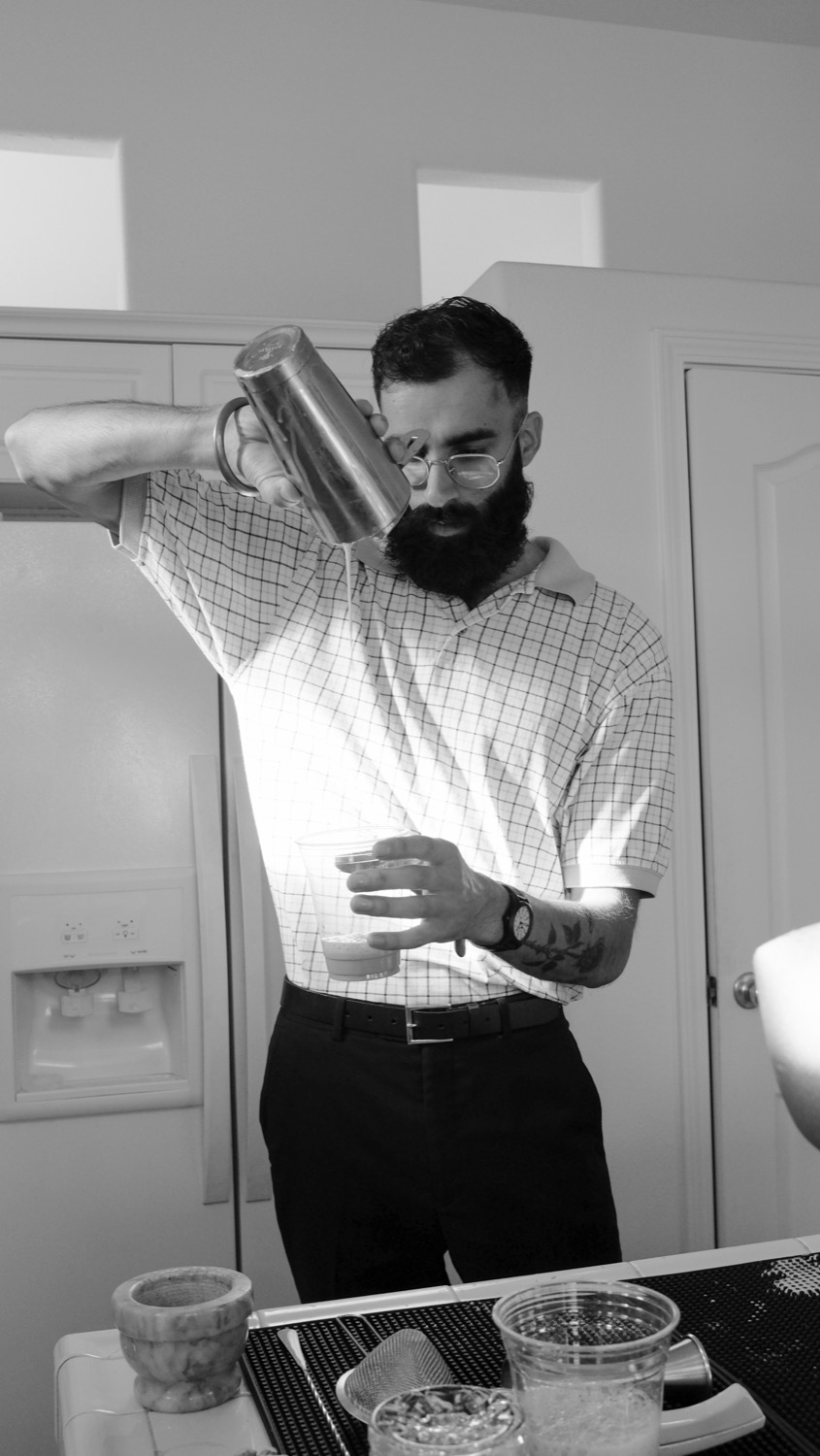 Chai strained from a steel tumbler into a cup, in black and white