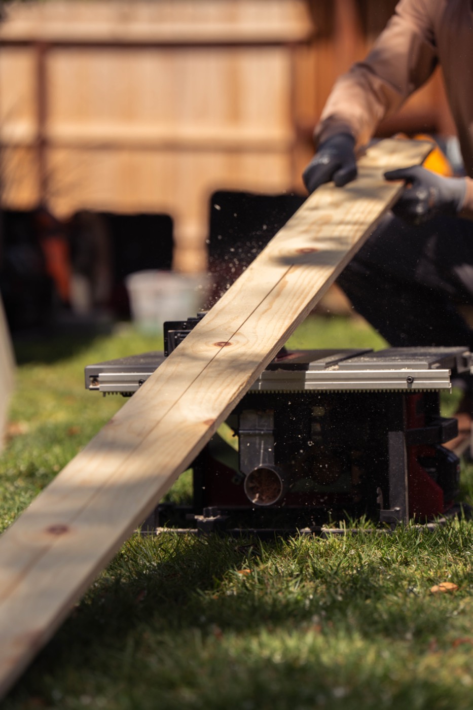A length of timber run across a saw in a back garden during the pop-up cart build