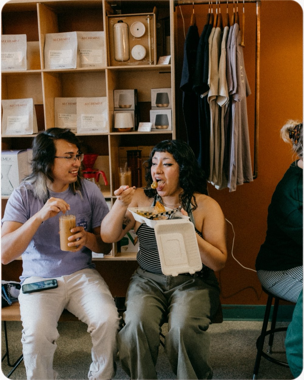 Two people sitting with iced chai and a box of pakoras at a Hatti pop-up