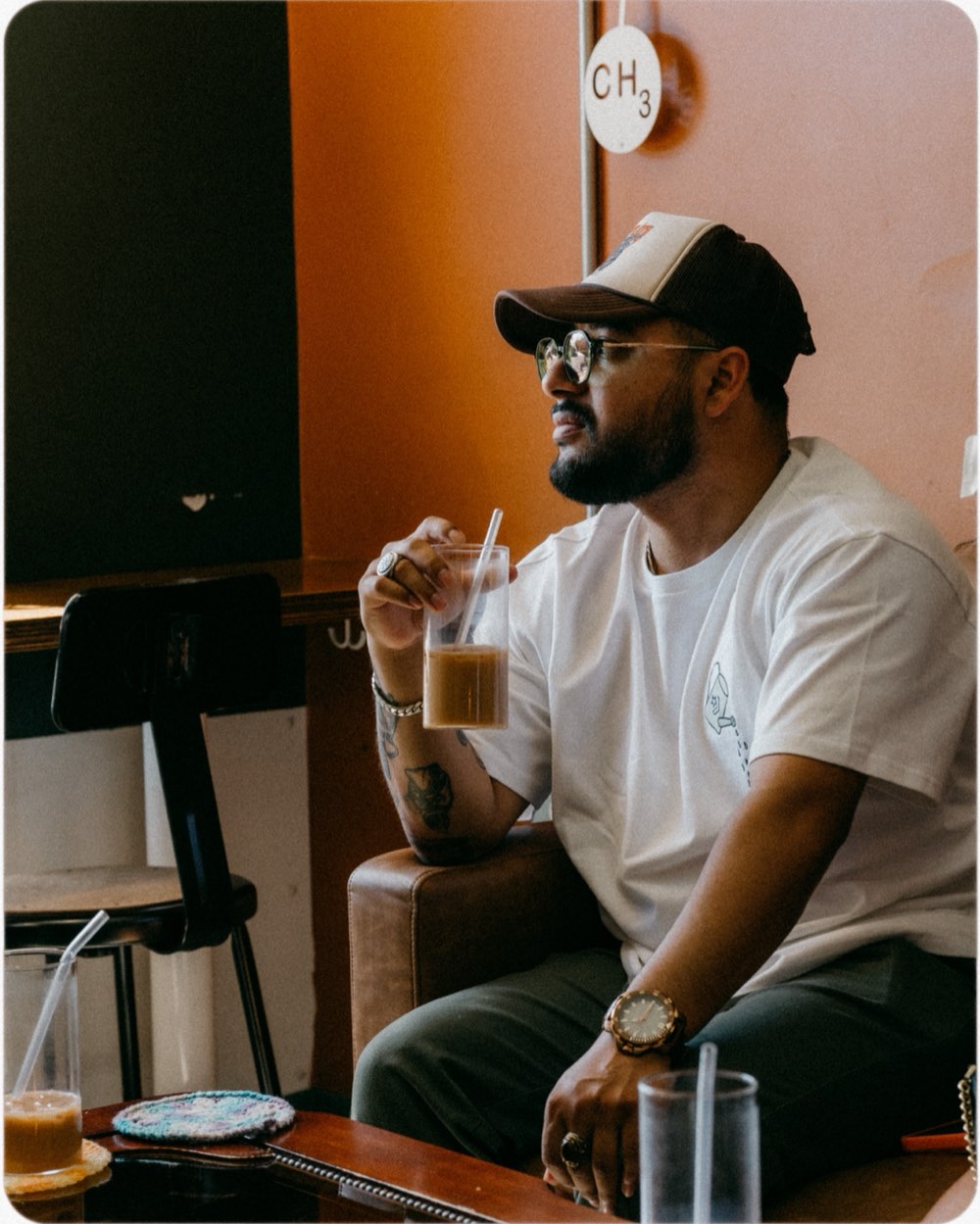 A man sitting with a glass of iced chai at a Hatti pop-up